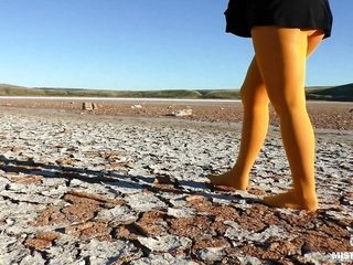 Shoeless walking by dried up lake in yellow stocking